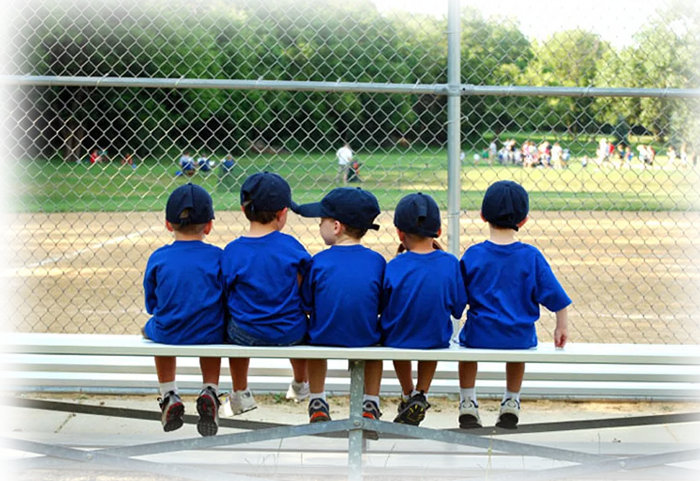 Four boys sitting together on a baseball bench